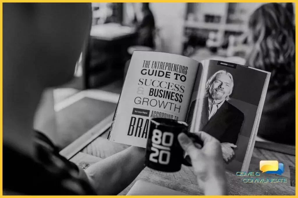 Chico sujetando una taza con una mano y con la otra leyendo el reportaje de una revista de Richard Branson