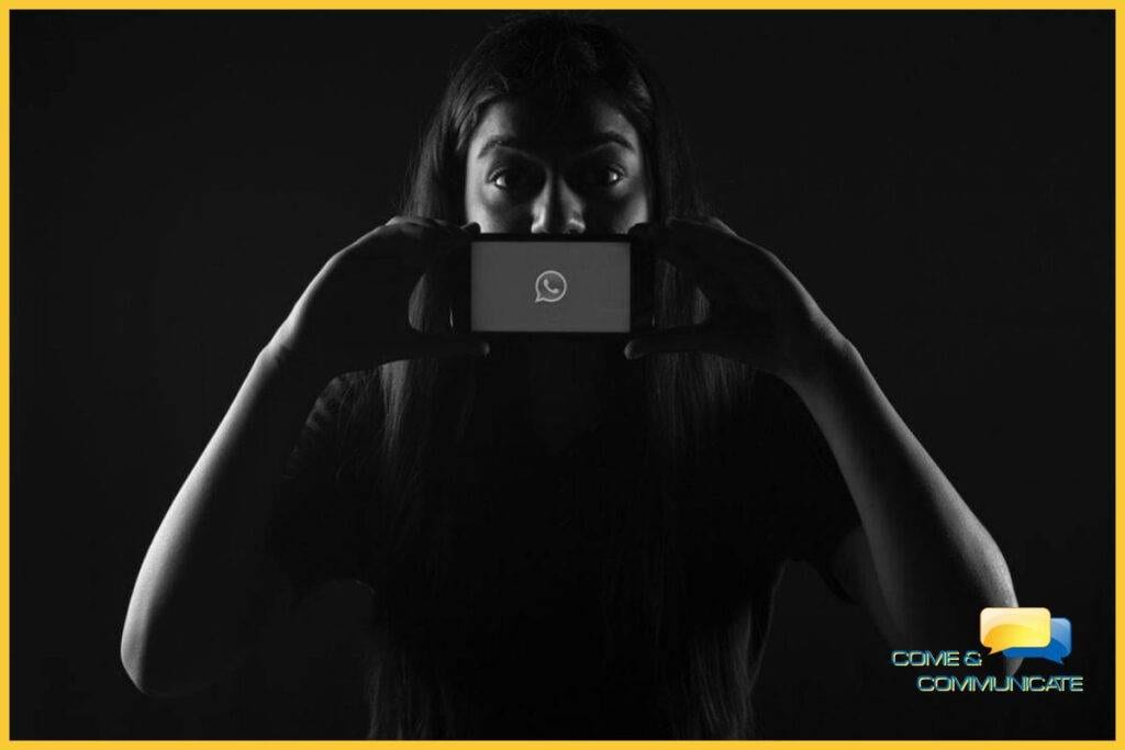 Chica tapándose la boca con el móvil donde se ve el icono de WhatsApp