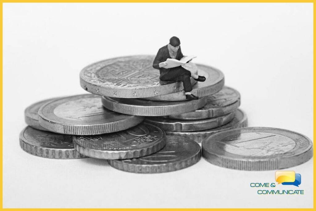 Figura de juguete leyendo el periódico encima de un montón de euros.