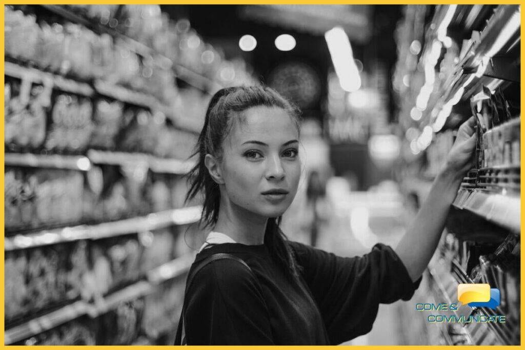 Mujer joven cogiendo un producto del lineal de un supermercado