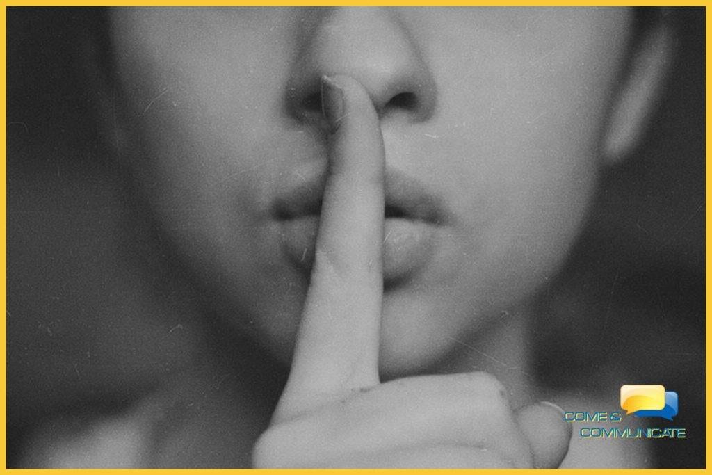 Cara de una mujer con el dedo índice en sus labios para hacer la señal de silencio.
