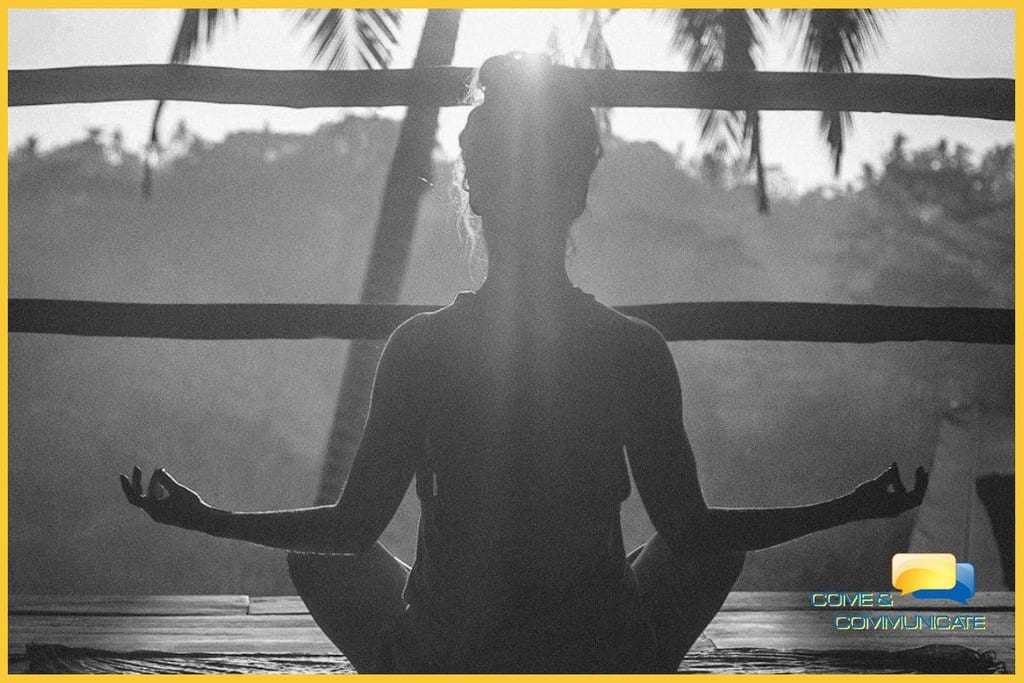 Contraluz de una chica meditando de cara al sol con los codos apoyados sobre sus rodillas