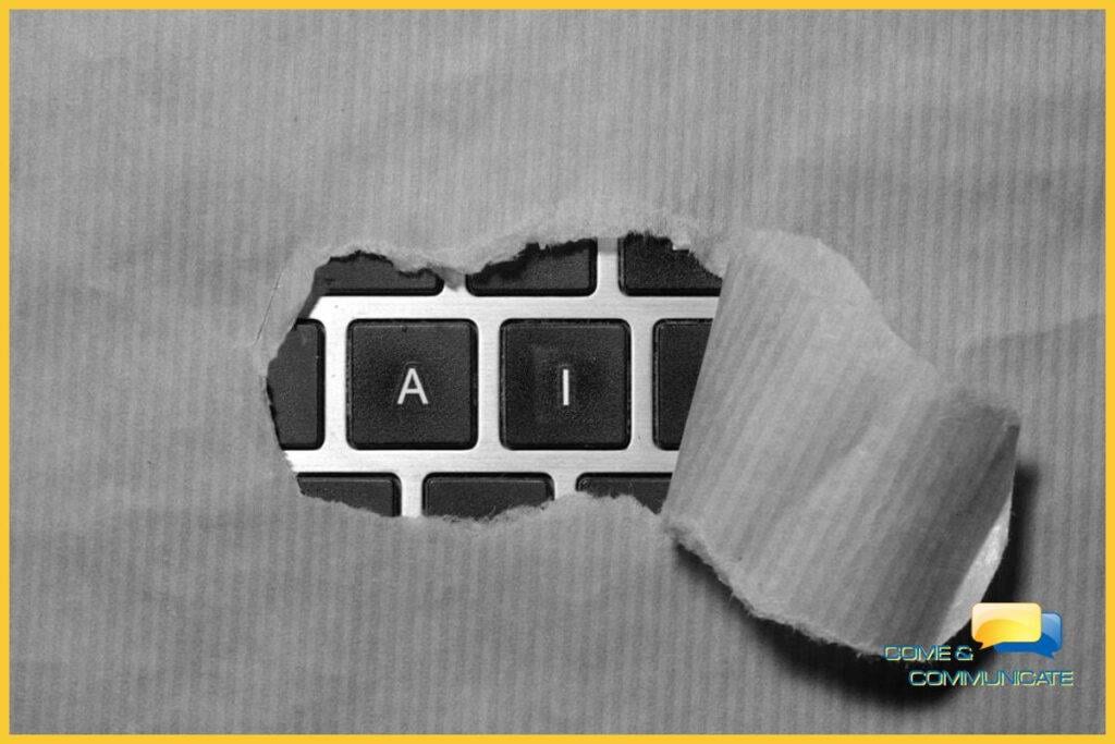 Fotografía conceptual en primer plano y blanco y negro de un teclado de portátil. Un papel rasgado revela únicamente las teclas 'A' e 'I', simbolizando el descubrimiento y la integración de la Inteligencia Artificial. Con el logo de Come & Communicate.